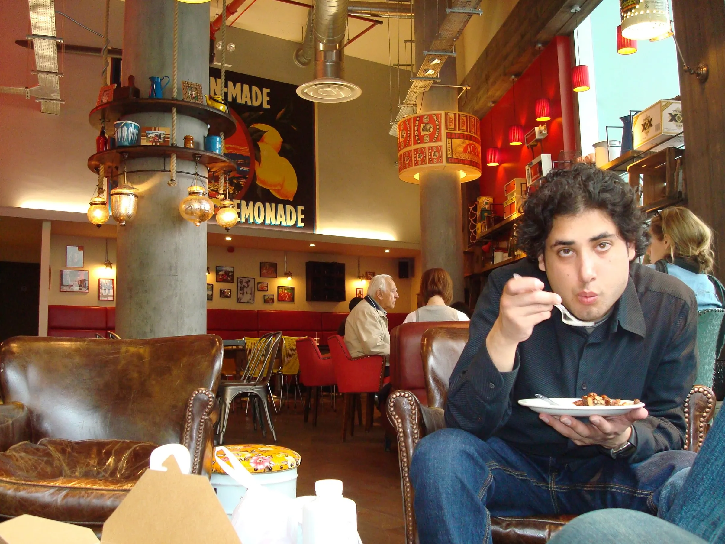 A young man eating from a plate in a busy café