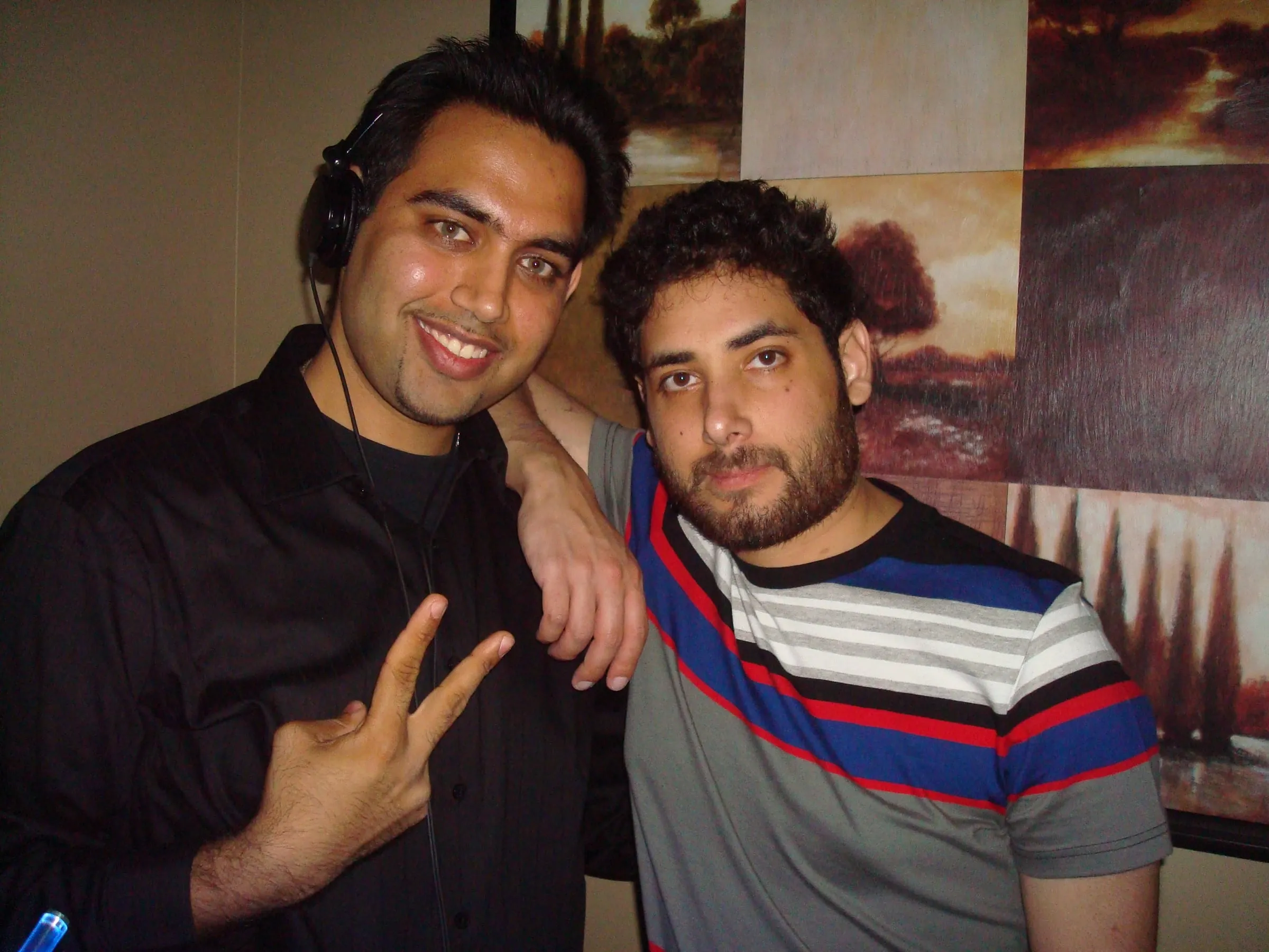 Two young men posing together, one making a peace sign