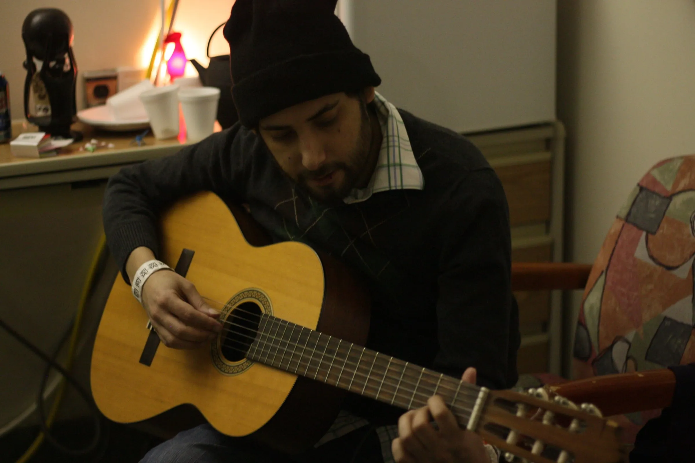 A man in a knit hat playing an acoustic guitar