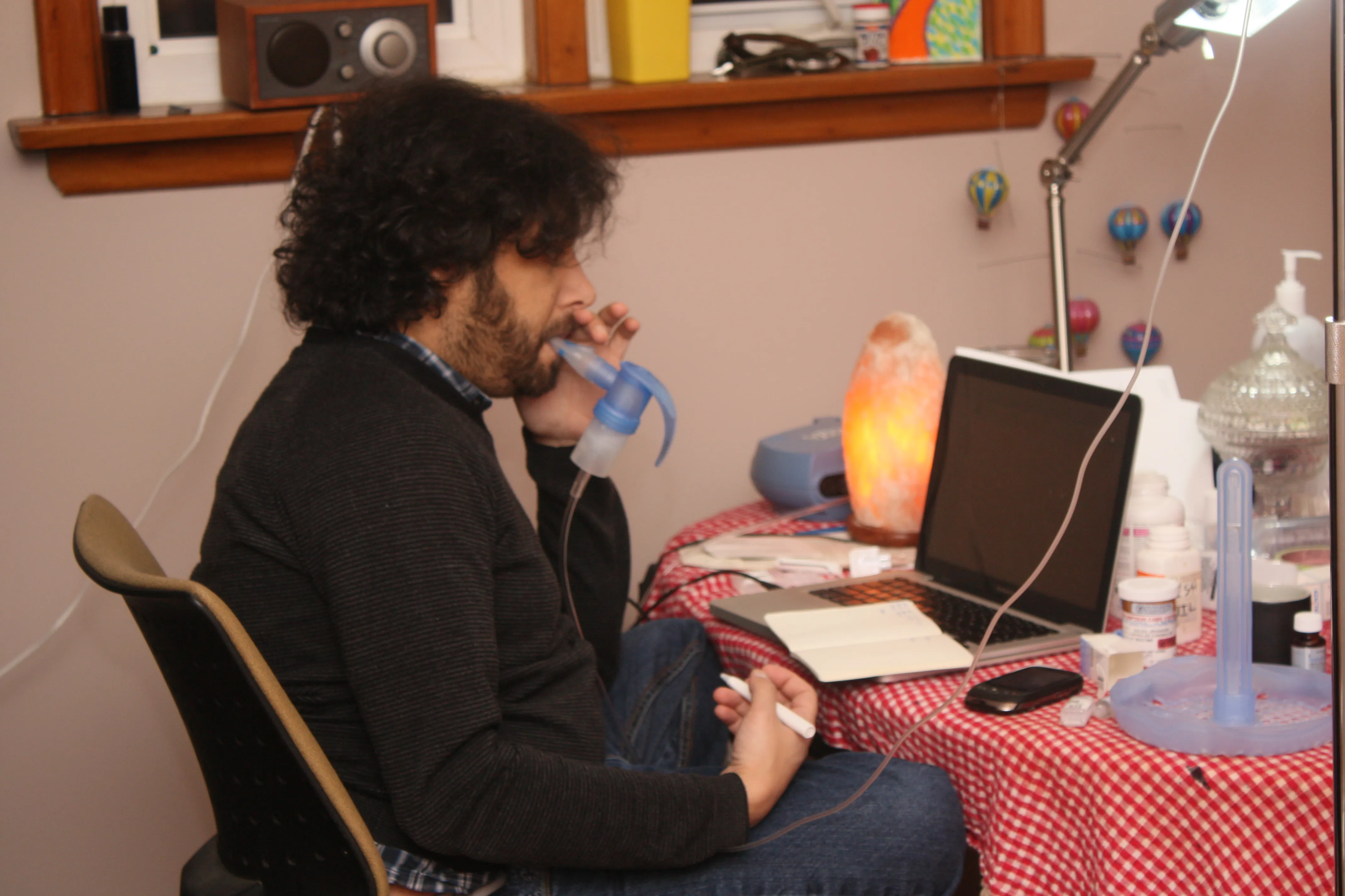 Jehangir at a laptop, breathing through a nebulizer mask